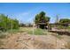 Large grassy area with weeds and an old shed. The property has a frame with bars surrounding the perimeter at 2921 N 103Rd Ave, Avondale, AZ 85392