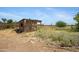 Small, old shed structure with a covered area behind it. Land has weeds at 2921 N 103Rd Ave, Avondale, AZ 85392
