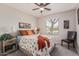 Bedroom with a ceiling fan, carpet, and a floral patterned bedspread with orange pillows at 42022 W Cheyenne Dr, Maricopa, AZ 85138