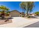 Single-Gathering home featuring desert landscaping, two-car garage, driveway, palm tree and rock accents at 42022 W Cheyenne Dr, Maricopa, AZ 85138