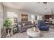 Open living area with view of the kitchen, grey sofa, accent chairs, and natural light at 42022 W Cheyenne Dr, Maricopa, AZ 85138