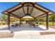 Spacious community pavilion features multiple picnic tables and sunshades with playground in the background at 42022 W Cheyenne Dr, Maricopa, AZ 85138