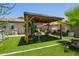 Backyard patio area with barbecue, artificial grass, potted plants, bar stools, and lighting at 518 S 114Th Ave, Avondale, AZ 85323