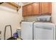 A laundry room with a washer, dryer, overhead cabinets, and a shelf on the wall at 518 S 114Th Ave, Avondale, AZ 85323
