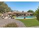 Expansive backyard with sparkling pool, covered patio, mature trees, and well-manicured lawn at 5410 E Poinsettia Dr, Scottsdale, AZ 85254