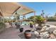 Inviting covered patio with dining area, beautiful rock waterfall, and lush landscaping surrounding pool at 5410 E Poinsettia Dr, Scottsdale, AZ 85254