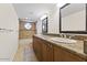 Bathroom with dual sinks, granite countertops, and bath/shower combo with a tile surround at 5450 E Paradise Ln, Scottsdale, AZ 85254