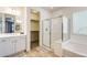 Bright bathroom featuring a glass-enclosed shower, a soaking tub, and a walk-in closet at 699 S 197Th Dr, Buckeye, AZ 85326