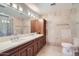 Bathroom with double sink vanity, wood cabinetry, decorative mirror, and stone-look wall tiles at 7151 E Rancho Vista Dr # 6002, Scottsdale, AZ 85251