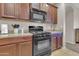 Well-lit kitchen with a black oven, microwave, granite countertops, and wooden cabinets at 742 E Kingbird Dr, Gilbert, AZ 85297