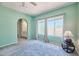 Light-filled bedroom provides an arched doorway, neutral carpet, and sunlit windows with tree top views at 750 E Northern Ave # 2088, Phoenix, AZ 85020