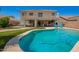 A sparkling pool with a home featuring a covered patio, seating, and manicured lawn in the background at 7923 W Hess Ave, Phoenix, AZ 85043