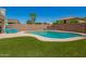 A backyard with a clear blue pool, artificial grass, palm trees, and a privacy wall at 7923 W Hess Ave, Phoenix, AZ 85043