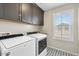 Functional laundry room with gray cabinets, washer, dryer, and a patterned tile floor at 880 S 150Th Dr, Goodyear, AZ 85338