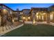 Beautiful home exterior featuring a stone facade, manicured lawn, outdoor dining, and elegant lighting at 9290 E Thompson Peak Pkwy # 470, Scottsdale, AZ 85255