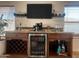 Stylish bar area with a mini fridge, granite counter, wine rack, glass storage, and a nearby workstation at 10029 S 44Th St, Phoenix, AZ 85044