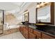 Beautiful bathroom with dual bowl sinks, granite countertops, tub, and large mirrors at 1192 E Sunset Dr, Casa Grande, AZ 85122