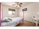 Bright bedroom with a four-poster bed, ceiling fan, and a window with natural light at 15792 W Desert Mirage Dr, Surprise, AZ 85379