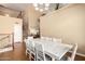 Bright dining room with a large white table, chairs, and a modern chandelier, adjacent to the staircase and second floor railing at 15792 W Desert Mirage Dr, Surprise, AZ 85379
