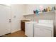 Laundry room with white washer and dryer, upper shelf, and tile flooring with a storage shelf at 15792 W Desert Mirage Dr, Surprise, AZ 85379