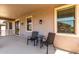 Relaxing covered patio with two chairs, a table, and views of the surrounding landscape at 15792 W Desert Mirage Dr, Surprise, AZ 85379