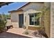 Side entryway featuring stone pavers, lush landscaping, a decorative door, and charming architectural details at 17082 S 182Nd Ave, Goodyear, AZ 85338