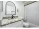 Well lit bathroom featuring a granite sink countertop, modern faucet, and shower with white curtain at 18818 N 12Th Ave, Phoenix, AZ 85027
