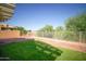 Lush green backyard with trees, gravel, fence and an area for relaxing, playing and entertaining at 19961 N Coyote Lakes Pkwy, Surprise, AZ 85378