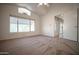 Bright bedroom featuring a vaulted ceiling, large window, and neutral carpeting at 19961 N Coyote Lakes Pkwy, Surprise, AZ 85378