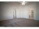 Spacious main bedroom features neutral carpet, a ceiling fan, and doorways to closets and the bathroom at 19961 N Coyote Lakes Pkwy, Surprise, AZ 85378