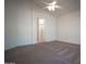 Large main bedroom boasts neutral carpet, a ceiling fan, and an archway leading to the en-suite bathroom at 19961 N Coyote Lakes Pkwy, Surprise, AZ 85378