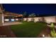 Beautiful backyard featuring a covered patio, artificial turf, and tasteful landscaping illuminated at nighttime at 20115 E Sonoqui E Blvd, Queen Creek, AZ 85142