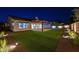 Beautiful backyard featuring a covered patio, artificial turf, and tasteful landscaping illuminated at nighttime at 20115 E Sonoqui E Blvd, Queen Creek, AZ 85142