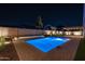 Beautiful pool with fountain features and tasteful landscaping with a covered patio illuminated at nighttime at 20115 E Sonoqui E Blvd, Queen Creek, AZ 85142
