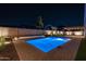 Beautiful pool with fountain features and tasteful landscaping with a covered patio illuminated at nighttime at 20115 E Sonoqui E Blvd, Queen Creek, AZ 85142