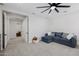 An open bonus room features plush carpet, ceiling fan, neutral paint and a comfortable blue couch at 20437 W White Rock Rd, Buckeye, AZ 85396