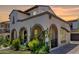 Elegant two-story home with stucco exterior, arched porch, and lush greenery at 20437 W White Rock Rd, Buckeye, AZ 85396