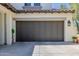 A home's garage features a dark wood door, concrete driveway, and trimmed overhang at 20437 W White Rock Rd, Buckeye, AZ 85396