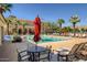 Community pool area with lounge chairs, umbrellas, tables, and a clear blue swimming pool at 20437 W White Rock Rd, Buckeye, AZ 85396