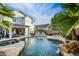 Backyard with a pool, waterfall feature, lounge areas, an outdoor seating area, and lush palm trees at 2056 E Carob Dr, Chandler, AZ 85286