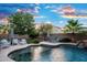 Inviting swimming pool with a rock waterfall, with comfortable seating areas and striped umbrellas at 2056 E Carob Dr, Chandler, AZ 85286