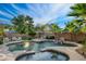 Beautiful backyard pool area with lounge chairs, waterfall feature, mature landscaping, and sunny skies at 2056 E Carob Dr, Chandler, AZ 85286