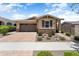 Charming single-story home with a two-car garage, brick driveway, and manicured landscaping at 20684 W Meadowbrook Ave, Buckeye, AZ 85396