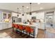 Modern kitchen with white cabinets, stainless steel appliances, large center island with orange chairs, and decorative pendant lighting at 20684 W Meadowbrook Ave, Buckeye, AZ 85396