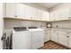 Functional laundry room with new, white Whirlpool washer and dryer set surrounded by white storage cabinets at 20684 W Meadowbrook Ave, Buckeye, AZ 85396
