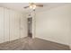 A carpeted bedroom with ceiling fan, double closet and door leading to another room at 2547 W Naranja Ave, Mesa, AZ 85202