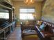 Cozy living room with wood-paneled wall, leather sectional, and entertainment center by window at 26314 N 103Rd Dr, Peoria, AZ 85383