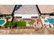 Aerial view of a backyard featuring a pool, pergola, manicured lawn and a cozy fire pit area at 30287 N 115Th Dr, Peoria, AZ 85383