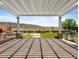 Inviting backyard space featuring a pergola, manicured lawn, and views of the surrounding desert landscape at 30287 N 115Th Dr, Peoria, AZ 85383