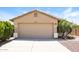 Home exterior featuring a two-car garage, desert landscaping, and tan stucco at 3750 S Conestoga Rd, Apache Junction, AZ 85119